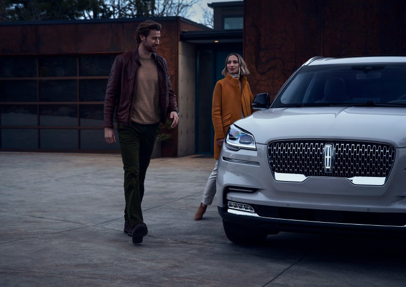 A man and a woman approaching a 2024 Lincoln Aviator® SUV, which illuminates certain lights when they are close | Lincoln Demo 3 in Wooster OH