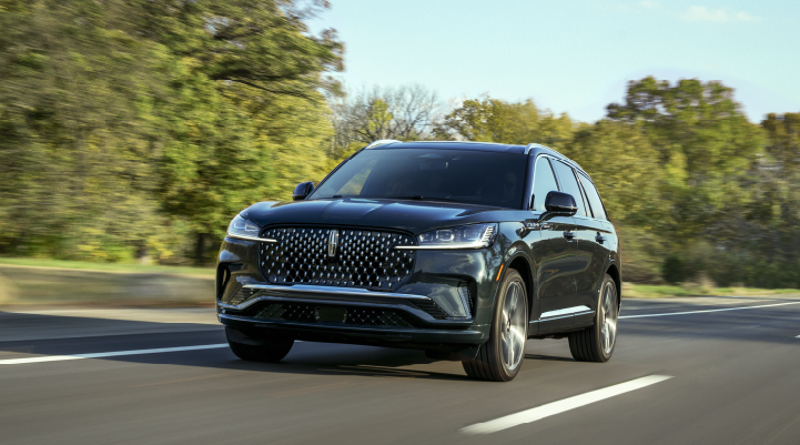 A 2025 Lincoln Black Label Aviator® SUV is being driven down a road lined with trees. | Lincoln Demo 3 in Wooster OH